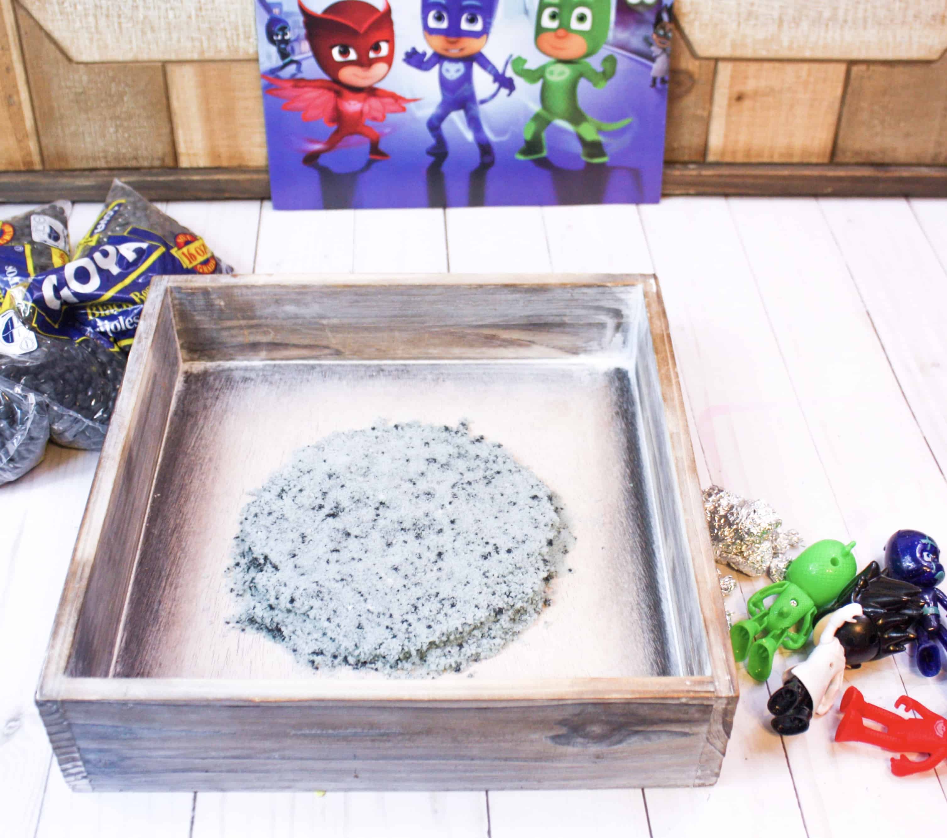This space sensory bin uses colored salt and beans to create a fun space scene for kids to play in. Play with the PJ Masks and their Mission to the Moon! #spacetheme #sensorybin #sensoryplay #preschool #toddlers #kidsactivities #preschoolfun